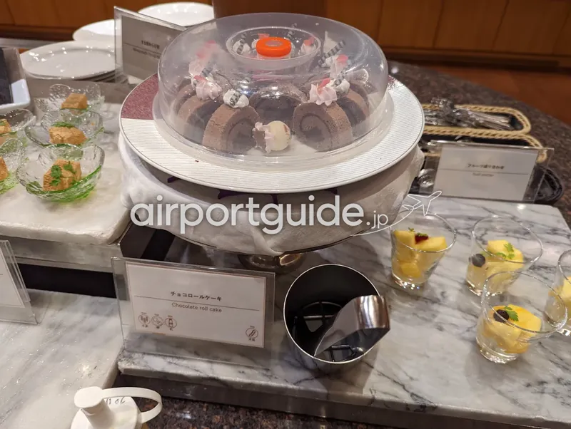 回転台の『チョコロールケーキ』とカットフルーツのカップが並ぶデザート台。