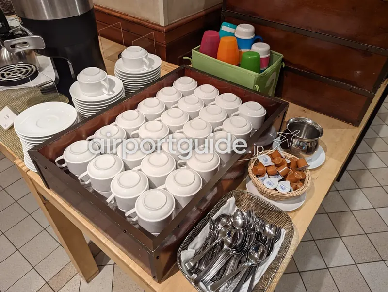 ドリンクコーナーのカップ類。コーヒーカップやスプーン、子供用カップが並ぶ。