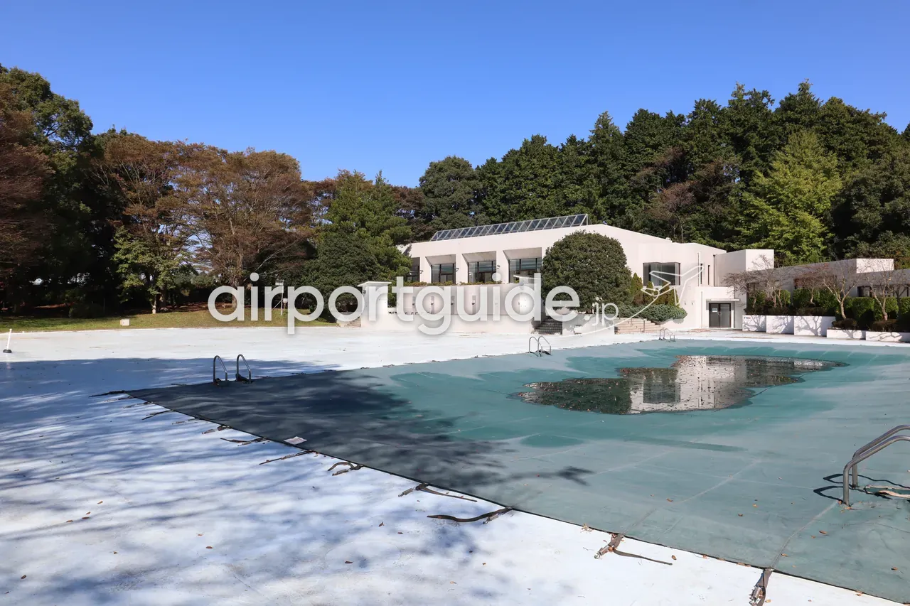 湯楽城の屋外プール。オフシーズンでシートがかけられ、奥に本館の建物、青空。