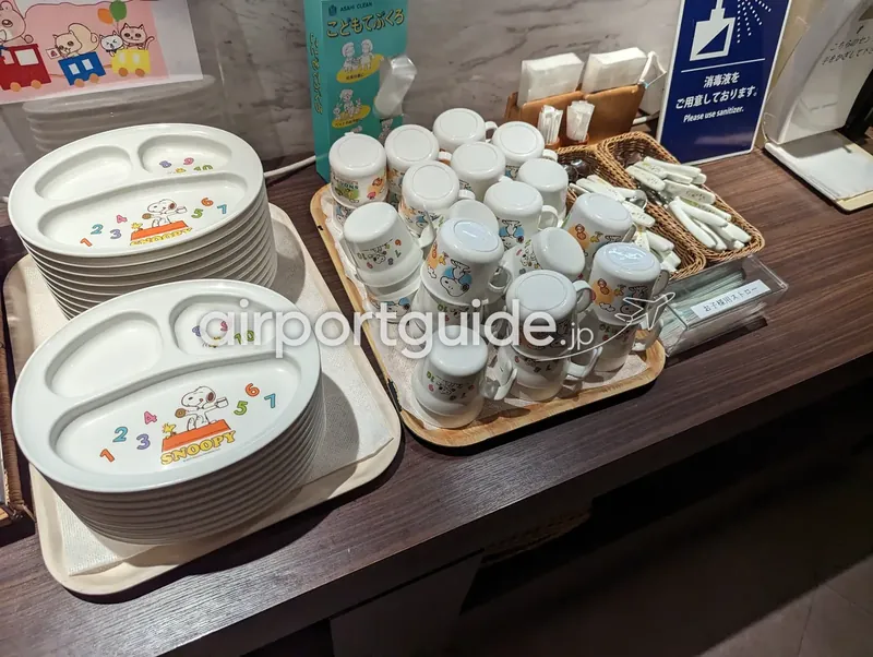 子ども用食器コーナー。スヌーピー柄の仕切り皿とキャラクターのマグカップが並ぶ。