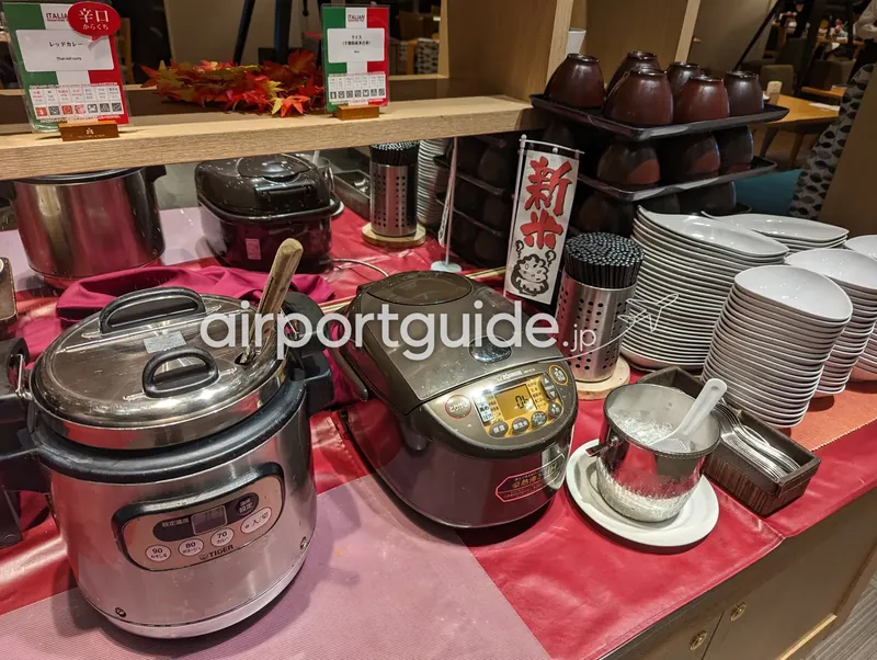 ご飯・カレーコーナー。炊飯器と保温ジャー、新米の幟。
