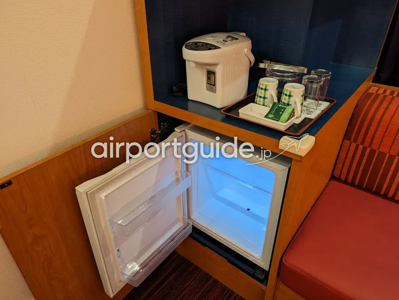 ホテル客室の備え付けミニ冷蔵庫（扉を開けた状態）と給湯ポット・湯呑みセット。