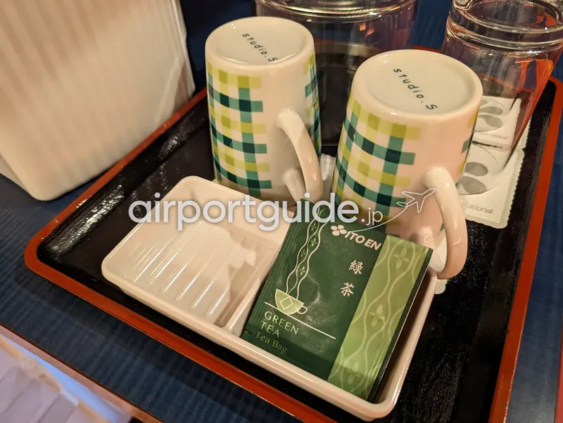 ホテル客室の湯呑みトレイのクローズアップ。ITO EN緑茶ティーバッグと「studio.S」マグ。