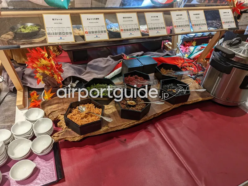 ホテル朝食のご飯のお供コーナー。鮭フレークや漬物、佃煮などが六角の器に並ぶ。