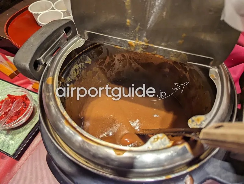 保温鍋を開けた、茶色いカレーのクローズアップ。