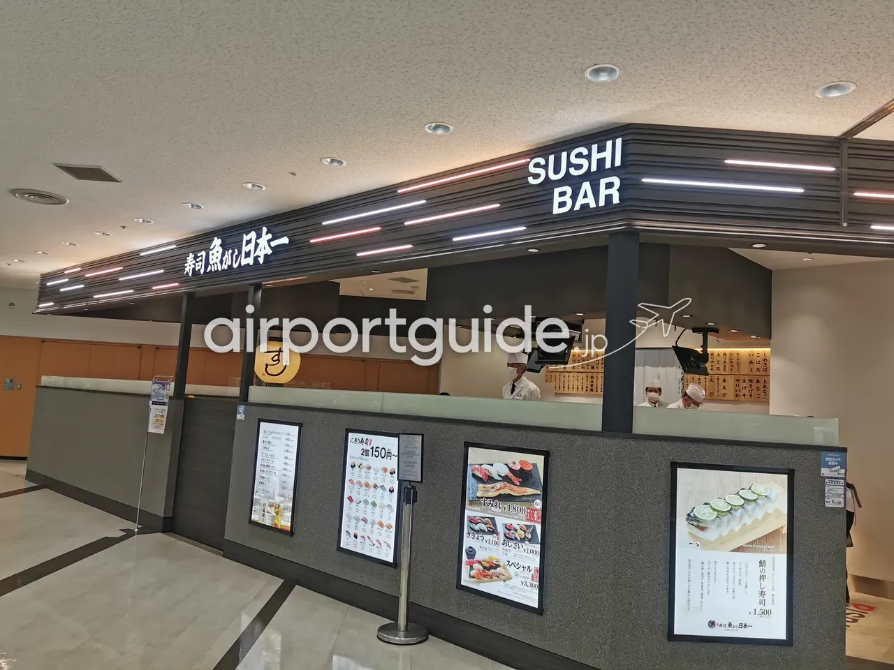 立ち食い寿司店「寿司 魚がし日本一 SUSHI BAR」の店頭。カウンター内で白衣の職人が握り、手前ににぎり寿司のメニュー掲示。