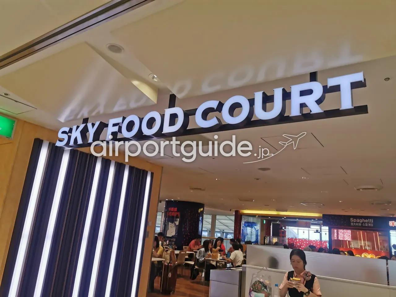 第1ターミナルの「SKY FOOD COURT（スカイフードコート）」。白い立体サインの下に、席で食事をする人々とスパゲッティ店などが見える。