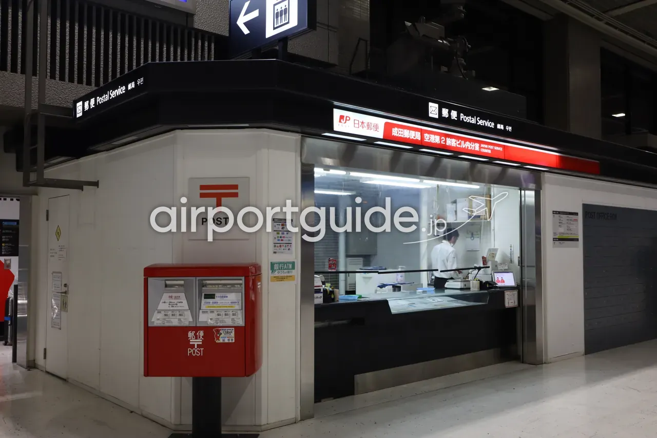 成田空港第2旅客ビル内の郵便局（日本郵便 成田郵便局 空港第2旅客ビル内分室）のカウンターと赤いポスト、ゆうちょ銀行ATMの案内。