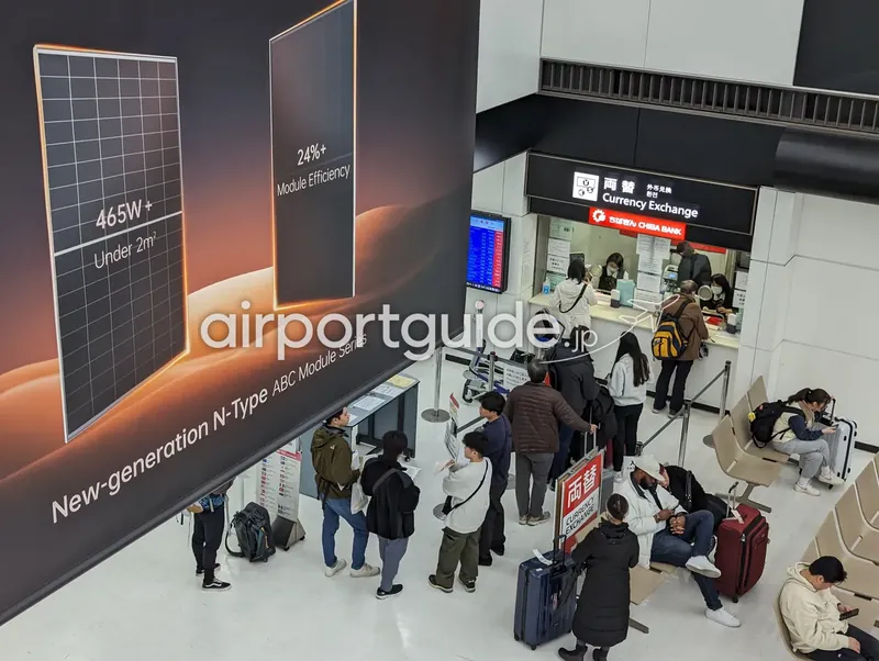 成田空港の千葉銀行外貨両替カウンターを上階から見下ろした様子。列を作る利用客と待合ベンチ。