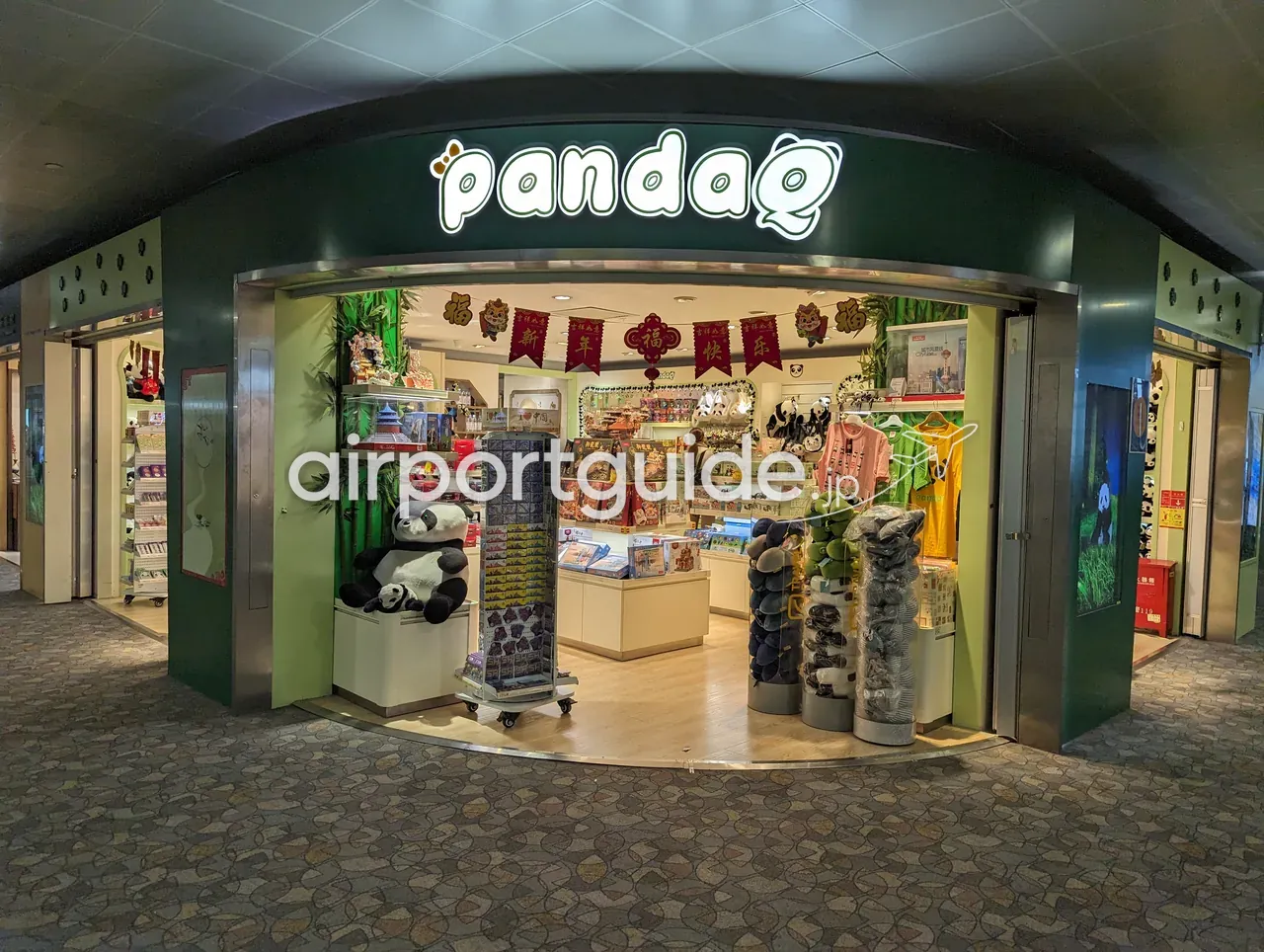 上海浦東空港のパンダ土産店『pandaQ』の店頭。パンダのぬいぐるみやTシャツ、菓子、上海の風景を描いたパネル、『新年快乐』の飾り。