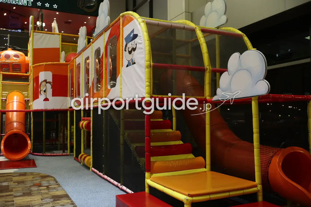 チャンギ空港の屋内キッズプレイエリア。電車をモチーフにした滑り台やトンネル付きのカラフルな遊具。