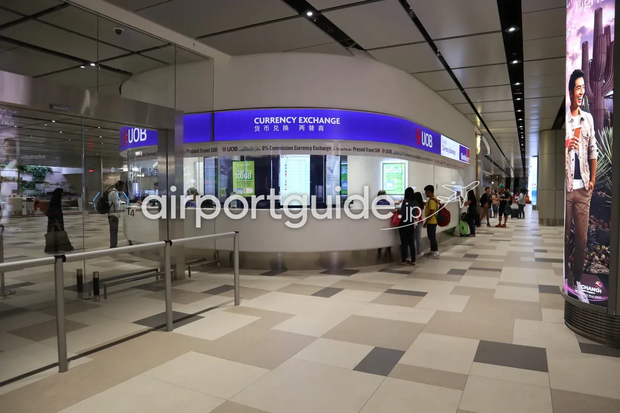 チャンギ空港のUOB両替カウンター。青い『CURRENCY EXCHANGE 货币兑换 两替商』の看板の下で、両替を待つ客が数人並んでいる。