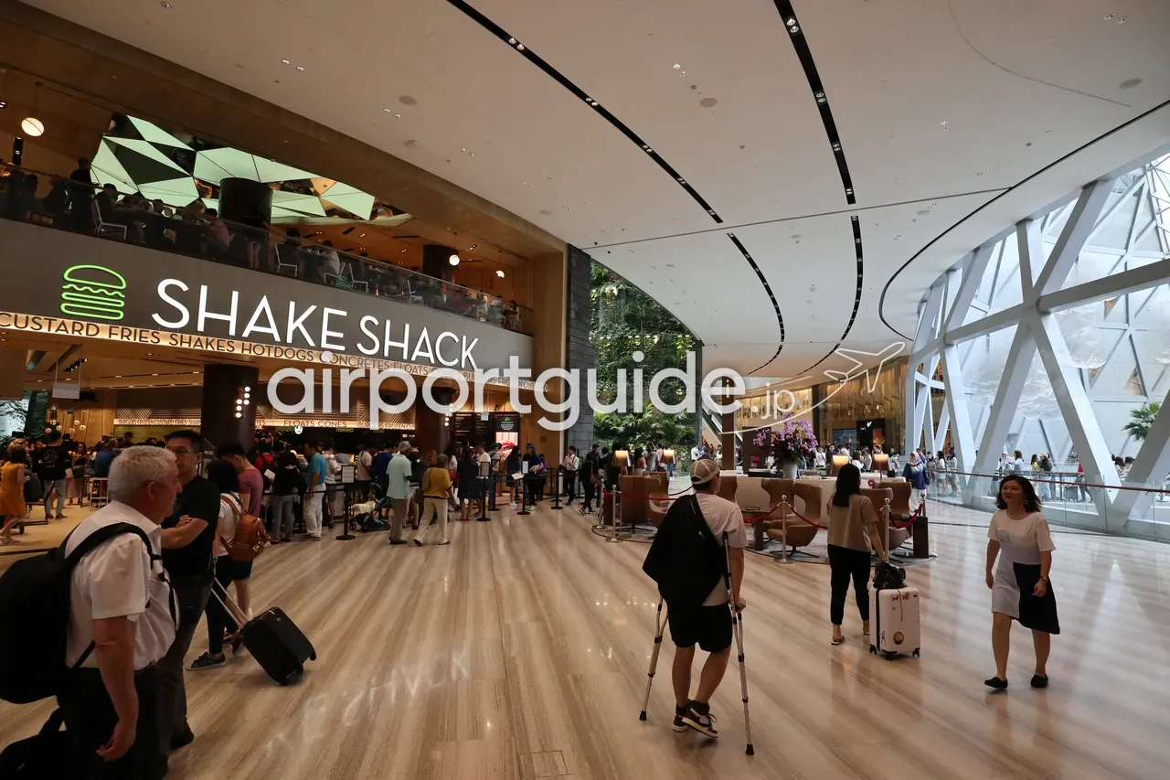 ジュエル・チャンギの「SHAKE SHACK」。緑のバーガーロゴの店頭に長い行列ができ、右手にジュエルのガラス外壁が見える。