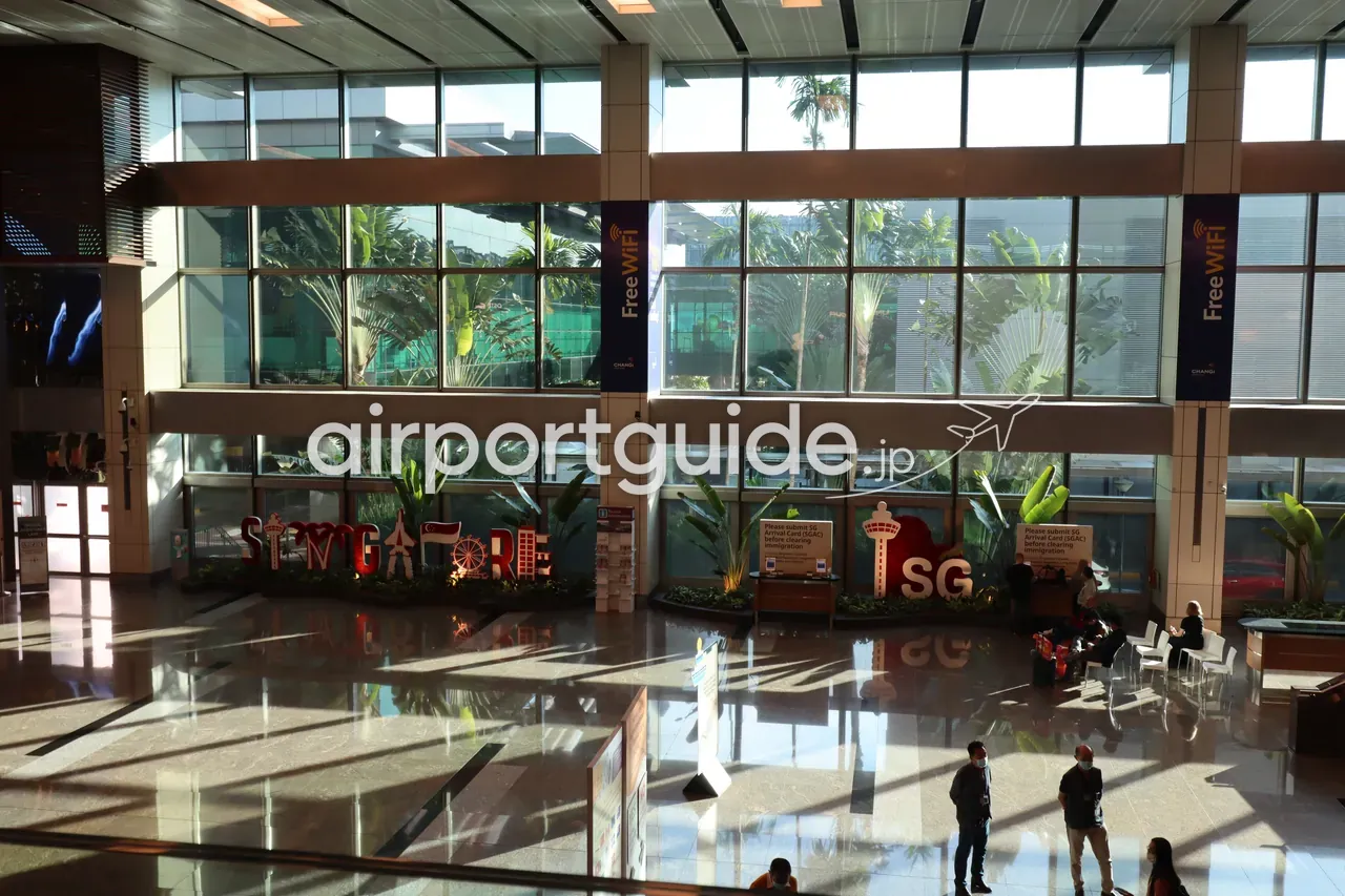 チャンギ空港の到着ホールの吹き抜け。赤白の立体レター「SINGAPORE」とハート型の「SG」モニュメント、柱に「Free WiFi」のバナー、ガラス越しに熱帯の植栽。