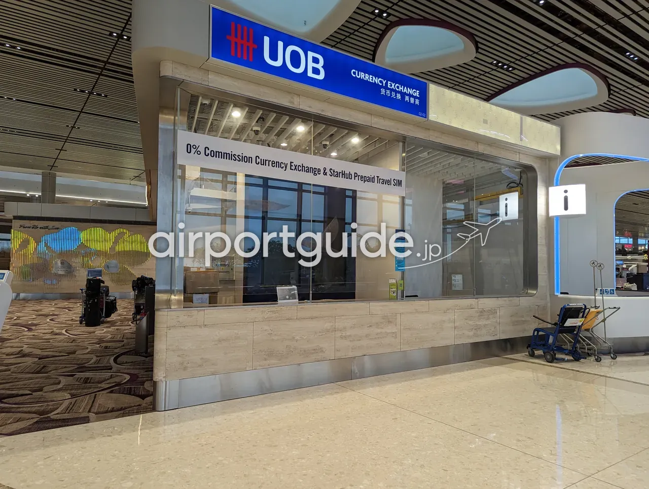 チャンギ空港ターミナル4（T4）のUOB Currency Exchangeの両替ブース。ガラス張りの窓口に『0% Commission Currency Exchange & StarHub Prepaid Travel SIM』の表示があり、すぐ隣にインフォメーション（i）カウンターが並ぶ。