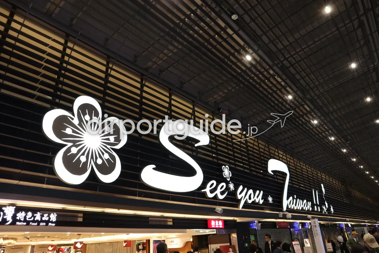 桃園空港の土産物店「See you Taiwan!! 特色商品館（Native Food Gift Shop）」の照明サイン。梅の花をかたどった白いロゴが黒い格子壁に光る。