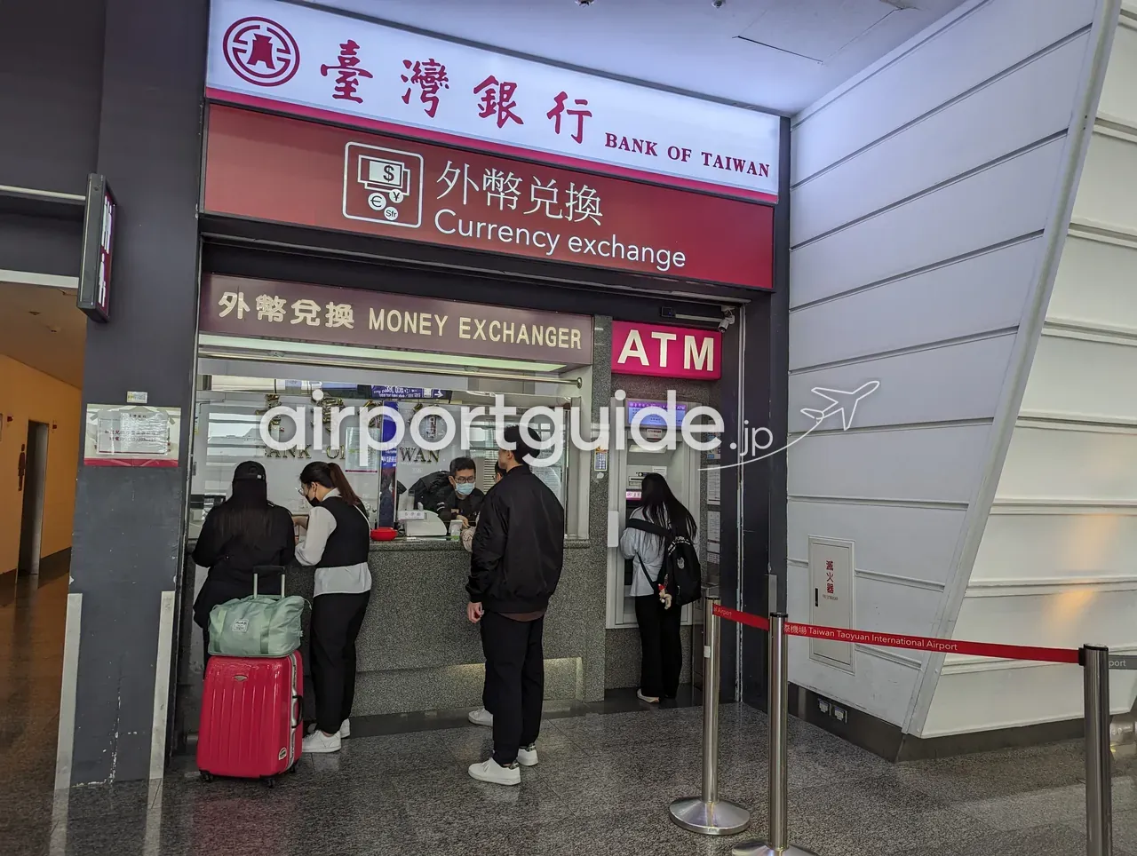 台湾桃園空港の到着エリアにある臺灣銀行(BANK OF TAIWAN)の外貨両替窓口「外幣兌換/Currency exchange」。右手にATMが並び、スーツケースを引いた旅客が窓口に並んでいる。