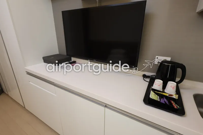テレビ台のウェルカムトレイ。電気ケトルと紙コップ、コーヒー・紅茶のスティック。